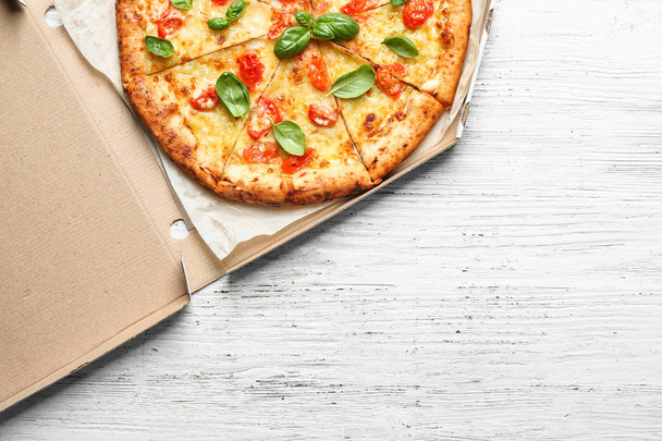 Caja de cartón con deliciosa pizza Margherita sobre fondo de madera
 - Foto, imagen