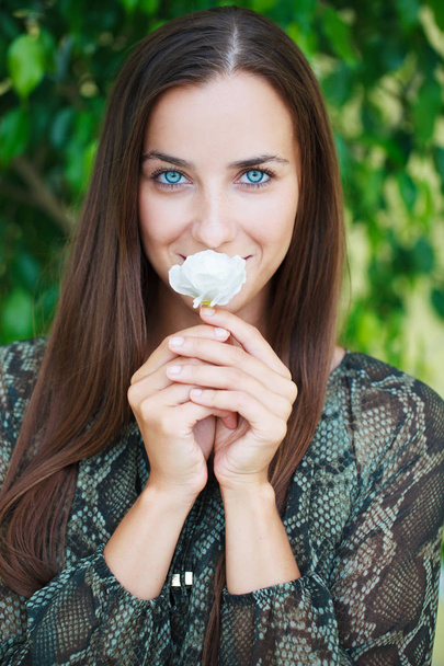 One white flower. Portrait of a beautiful young woman on a background of green leaves, summer outdoors - Photo, Image