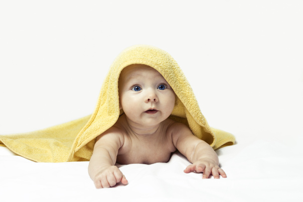 Adorable enfant heureux aux yeux bleus dans une serviette jaune sur fond blanc. - Photo, image