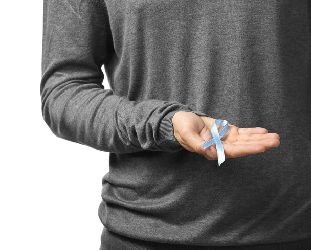Άνθρωπος που κρατά την μπλε κορδέλα σε άσπρο φόντο, κινηματογράφηση σε πρώτο πλάνο. Η έννοια του καρκίνου του προστάτη - Φωτογραφία, εικόνα