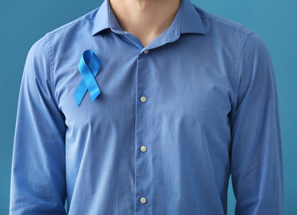 Man with symbolic blue ribbon on color background. Prostate cancer concept - Foto, Imagem