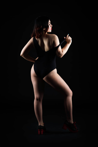 Beautiful sexy woman in bodysuit posing on black studio background, perfect female body, low key studio shot - Fotografie, Obrázek