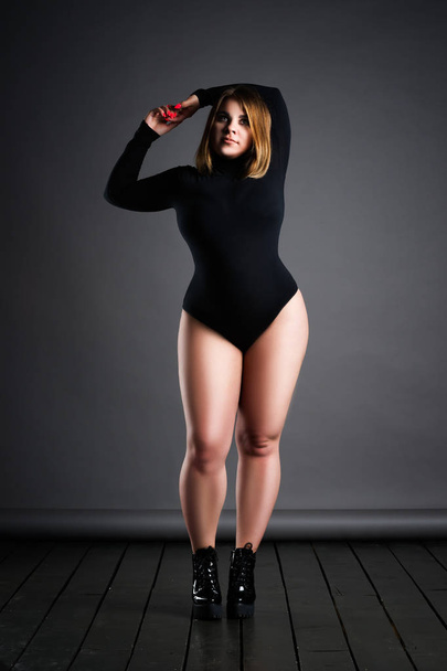 Plus size sexy model in black bodysuit, fat woman on gray studio background, overweight female body, full length portrait - Foto, afbeelding