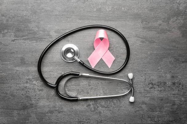 Pink ribbon and stethoscope on grey background. Breast cancer awareness concept - Photo, Image