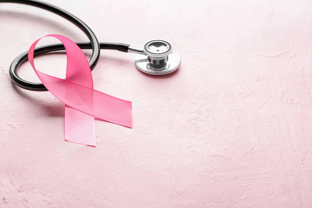 Pink ribbon and stethoscope on color background. Breast cancer awareness concept - Foto, imagen