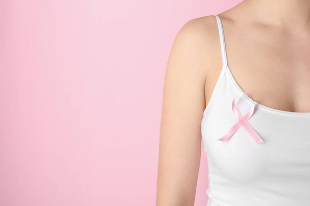 Woman with pink ribbon against color background. Breast cancer awareness concept - Foto, Bild