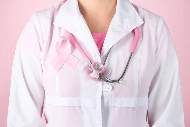 Доктор с розовой лентой на халате на цветном фоне. Концепция информированности о раке груди
 - Фото, изображение