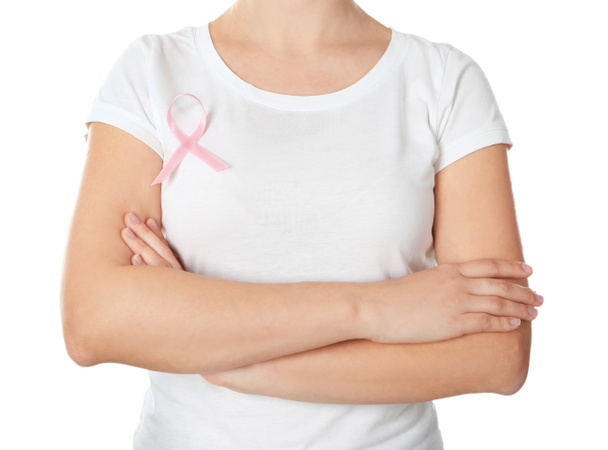 Woman with pink ribbon on t-shirt against white background. Breast cancer awareness concept - Photo, Image