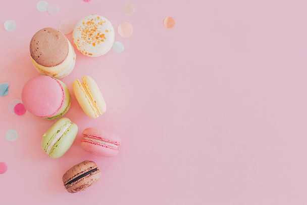 modern food photography concept. stylish colorful macaroons on trendy pink paper, flat lay. space for text.tasty pink, yellow, green, white, brown macarons. yummy background - Фото, изображение