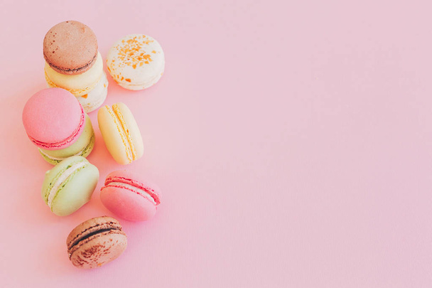 stylish colorful macaroons on trendy pink paper, flat lay. space for text. modern food photography concept. tasty pink, yellow, green, white, brown macarons. yummy background - Фото, изображение