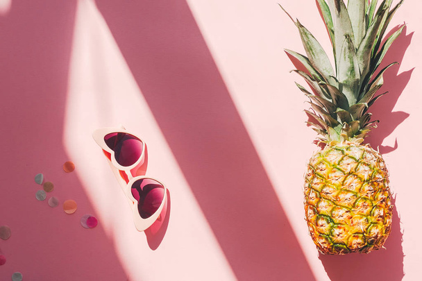 kesäloma ja juhla käsite. tyylikäs vaaleanpunainen aurinkolasit ja ananas trendikkäällä vaaleanpunaisella paperilla taustalla auringonvalossa. litteä. tilaa tekstille. matkustaminen ja vaeltaminen
 - Valokuva, kuva