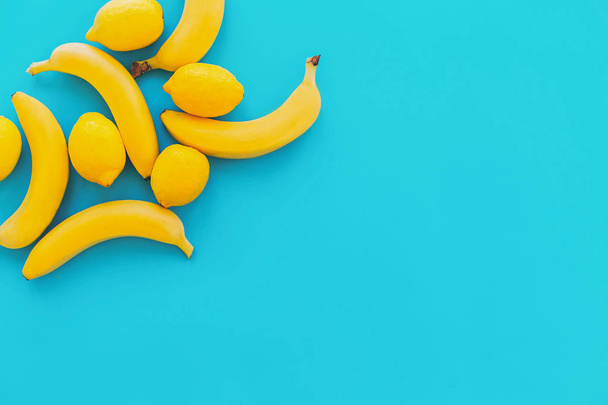 yellow bananas with lemons on blue paper trendy background, flat lay. bright summer flat lay concept, with space for text. juicy abstract background, pop art style. modern image - Zdjęcie, obraz