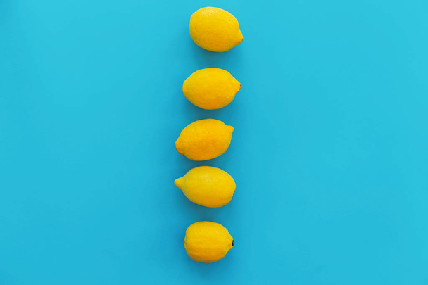 gelbe Zitronen in einer Reihe auf blauem Papier trendy Hintergrund, flache Lage. helles Sommerflach-Verlegekonzept, mit Platz für Text. saftig abstrakten Hintergrund, Pop-Art-Stil. Modernes Image - Foto, Bild