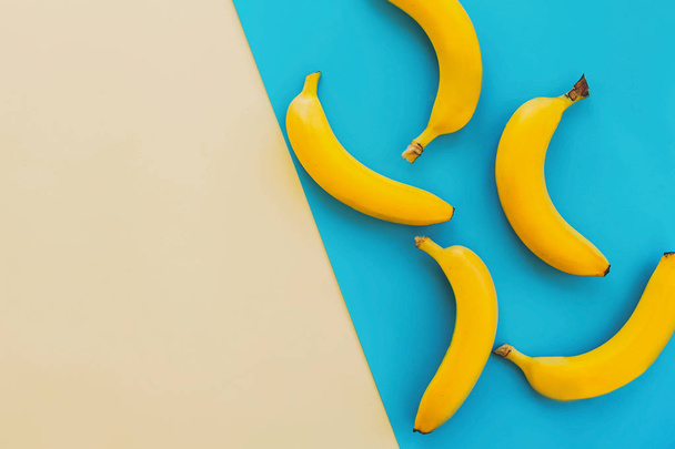 summer flat lay. yellow bananas on blue paper trendy background, flat lay. bright colorful photo, with space for text. juicy abstract background, pop art style. modern image - Foto, Imagen