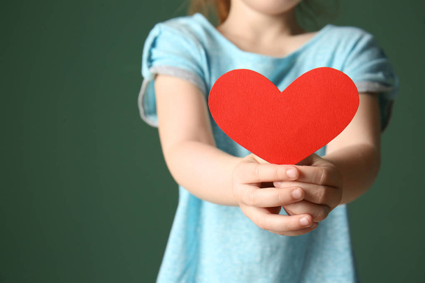 Little girl with red paper heart on color background, closeup - Photo, Image