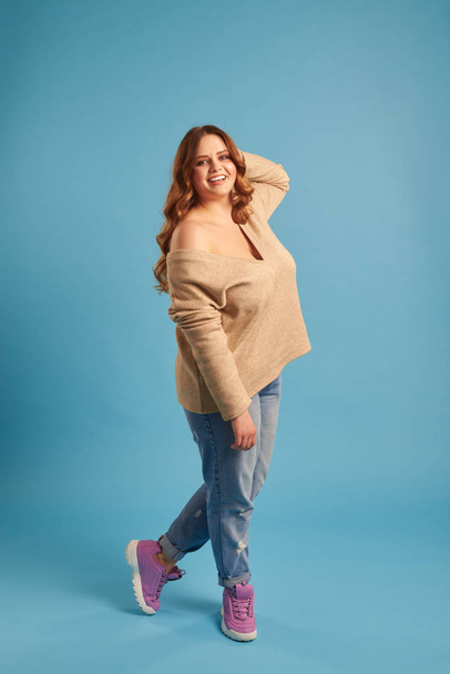 Candid young plus-size girl posing against blue background  - Photo, image