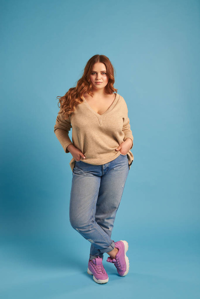 Vertrouwen mollig meisje in jeans en trui poseren in studio - Foto, afbeelding