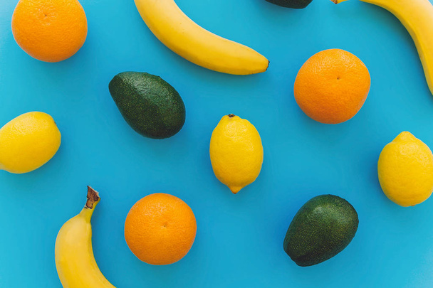 bananas, laranjas, limões, abacate no fundo azul da moda papel flat lay. conceito de fruta multi verão, padrão colorido. estilo de vida saudável e vibrações de férias
. - Foto, Imagem