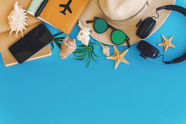 Plánujete letní dovolenou plochý ležela. Stylový černý telefon, pas, sluneční brýle, mapy, klobouk, sluchátka, granáty, notebook v módním modrém papíře. prostor pro text. cestování a toulavost - Fotografie, Obrázek