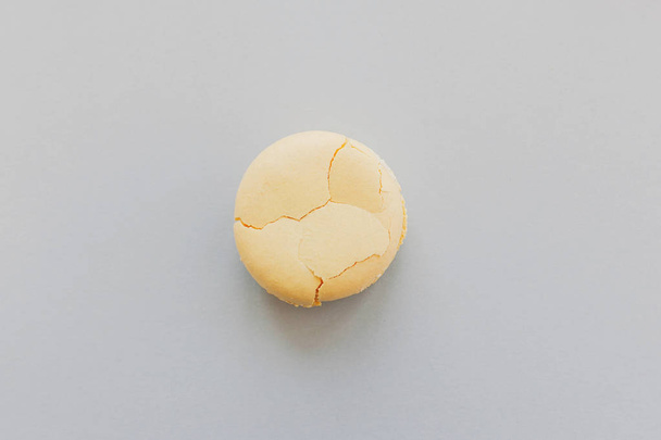 delicious yellow macaroon with cracks on trendy pastel gray paper, flat lay. tasty yellow macaron. space for text. luxury catering - Foto, afbeelding