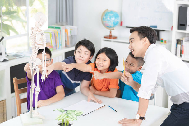 Aasialainen opettaja selittää ihmiskehon rakennetta pienelle oppilaalle
. - Valokuva, kuva