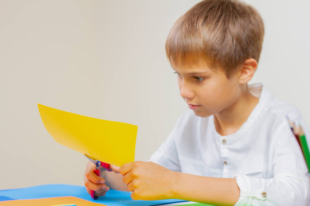 Lapsen leikkaus värillinen paperi sakset pöydässä
 - Valokuva, kuva