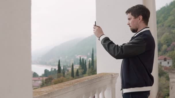 mies ottaa kuvia maiseman puhelimessa, jonka hän näkee ikkunan läpi
 - Materiaali, video