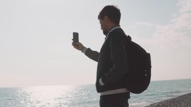 nuori valokuvaaja ottaa valokuvia älypuhelimella, herrasmies on merellä
 - Materiaali, video