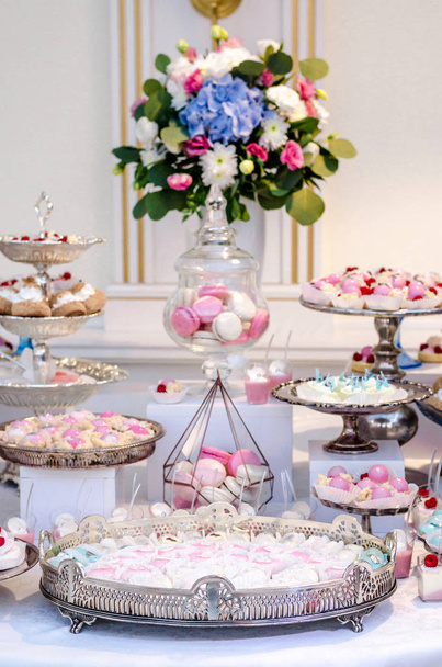 Lezzetli düğün Resepsiyon şeker çubuğu tatlı masa kekler ve tatlılar ve ortanca bir çiçek vazo ile dolu. Lüks yaşam. - Fotoğraf, Görsel