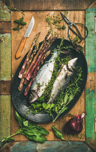 Fischessen kochen. roh gekochter Wolfsbarsch mit Kräutern und Gemüse vor rustikalem Holzhintergrund - Foto, Bild