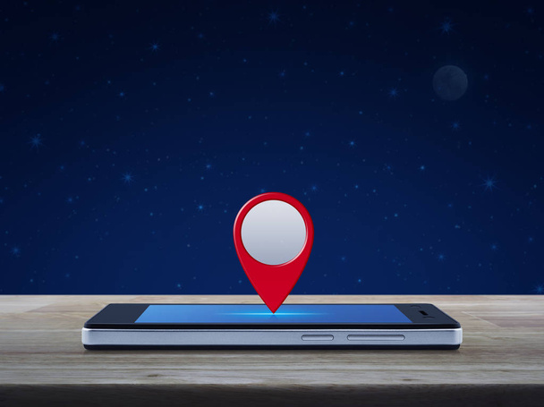 Map pin location button on modern smart phone screen on wooden table over fantasy night sky and moon, Map pointer navigation concept - Foto, Bild