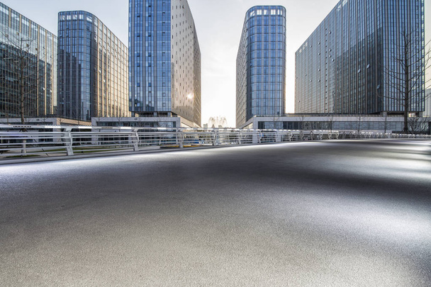 Panoramik siluet ve boş yolu, boş beton zemini olan modern iş binaları. - Fotoğraf, Görsel