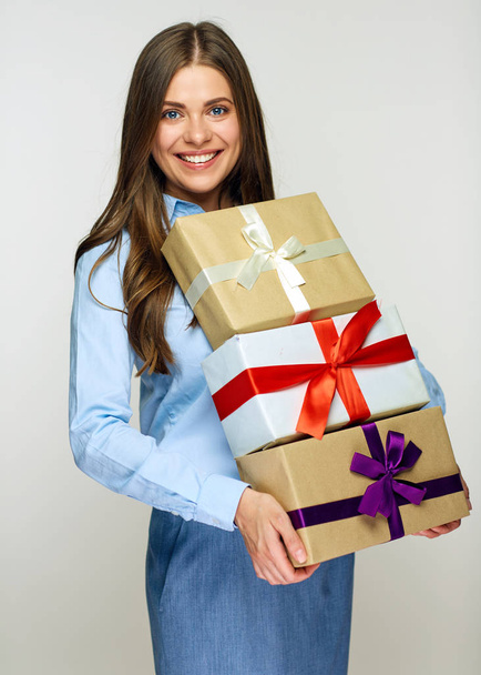 Businesswoman wearing blue shirt and grey skirt holding pile of gift boxes  - 写真・画像