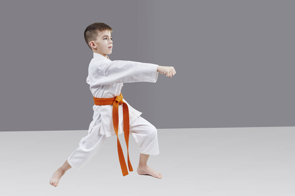 A boy with an orange belt is beating blow hand - Photo, Image