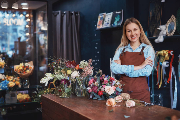 Jeune fleuriste souriant dans un tablier dans le magasin
 - Photo, image