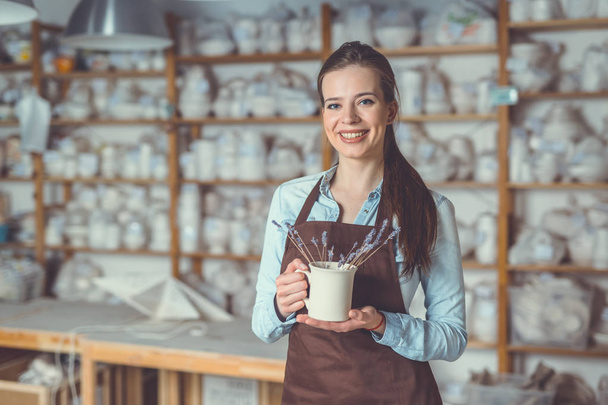 усміхнена молода дівчина з керамічною вазою
 - Фото, зображення