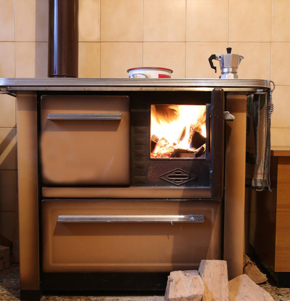 古い薪ストーブ火の赤夜萌香鍋が付いている家のキッチンで - 写真・画像