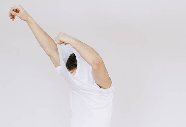 A young man takes off his T-shirt. isolated white background - Fotoğraf, Görsel