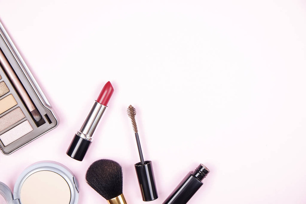 Feminine desktop top with bunch of cosmetics: eye shadow palette, brow mascara, brush, blusher powder w/ mirror. Woman's table top & her beauty accessories. Background, top view, flat lay, copy space - Photo, Image