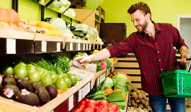 Caucasian man in red checkered shirt choosing vegetables in grocery - Foto, afbeelding