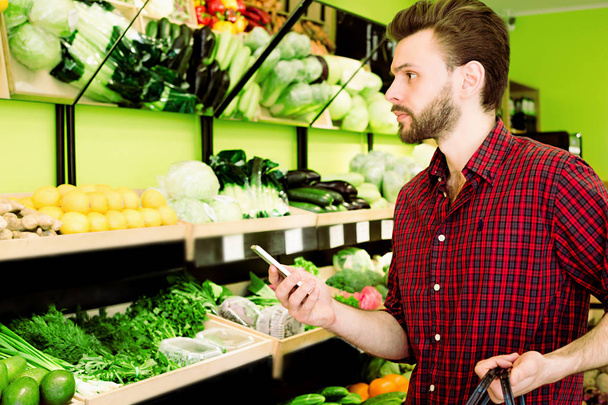 Caucasian man in red checkered shirt choosing vegetables in grocery - Φωτογραφία, εικόνα