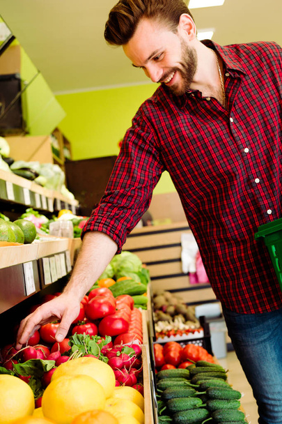 Caucasian man in red checkered shirt choosing vegetables in grocery - Foto, Imagem
