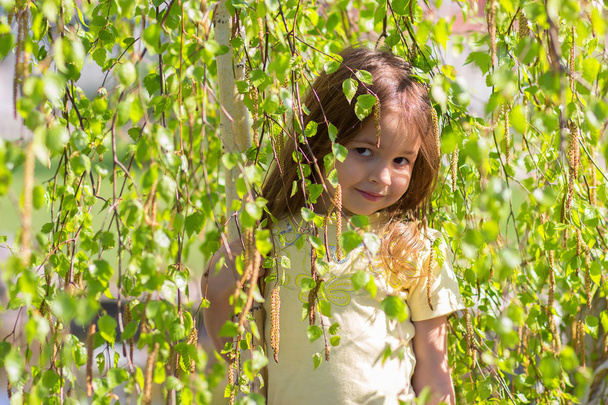 Portret van het meisje, vygladyvayushchy vanwege berk boomtakken - Foto, afbeelding