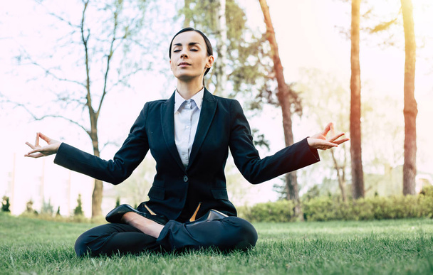 Young caucasian brunette businesswoman in suit meditating outdoors - Фото, зображення