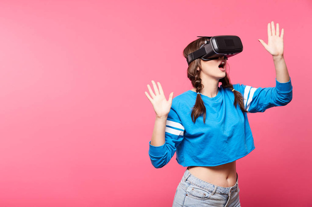 Nuori nainen virtuaalitodellisuus lasit poseeraa vaaleanpunainen tausta, 3D, tulevaisuuden konsepti
 - Valokuva, kuva