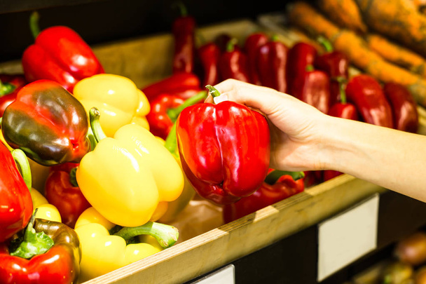 Womans hand choosing peppers in grocery - 写真・画像