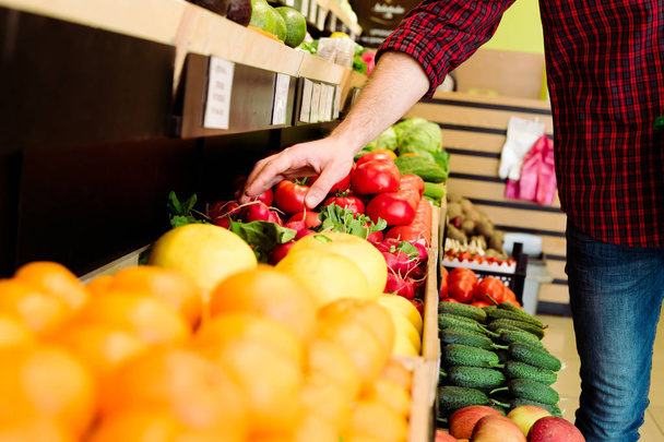 Caucasian man in red checkered shirt choosing vegetables in grocery - Foto, Bild