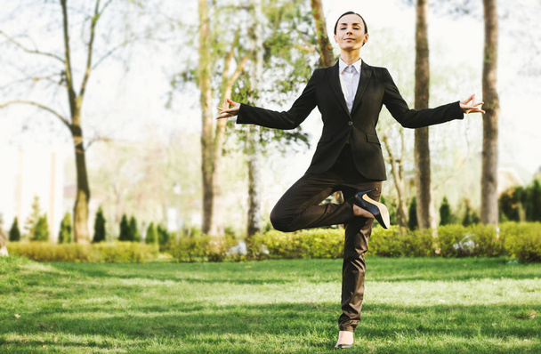 Young caucasian brunette businesswoman in suit practicing yoga outdoors - Foto, imagen