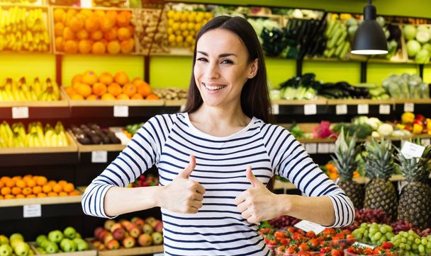 young woman posing in supermarket on fruits and vegetables background - Zdjęcie, obraz