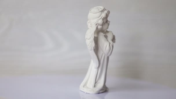 λευκό Άγγελος άγαλμα περιστρέφεται σε μια στάση σε ένα λευκό ξύλινο τοίχο. 4 k βίντεο μορφή - Πλάνα, βίντεο